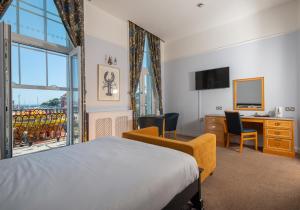 a hotel room with a bed and a desk and a window at Hotel Rex in Weymouth