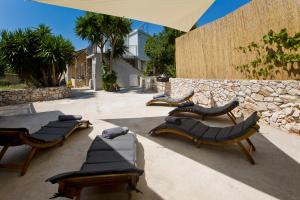 a group of chairs and tables in front of a stone wall at Robinson house T'n'T in Hvar
