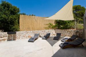a patio with lounge chairs and a large umbrella at Robinson house T'n'T in Hvar