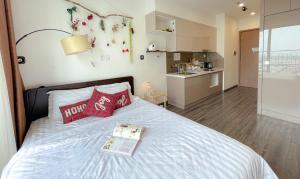 een slaapkamer met een bed met een boek en een keuken bij Monday Homestay -R103 Vinhomes Ocean Park-Gia Lam-Ha Noi in Gia Lâm Pho