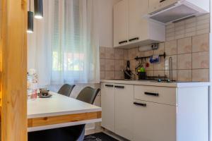 a kitchen with white cabinets and a table and chairs at Apartments Villa Bazilika in Sečovlje
