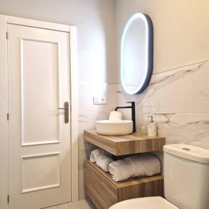 een badkamer met een wastafel, een toilet en een spiegel bij Apartamento Plaza Cervantes in Jaén
