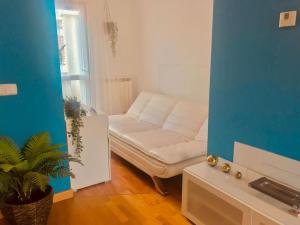 a living room with a white couch and a blue wall at PENTHOUSE INDEPENDIENTE a 3 paradas en metro de ATOCHA (estacion central Madrid) in Madrid