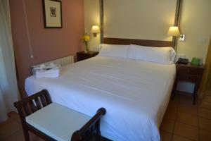 a bedroom with a large white bed with a chair at Jardines de La Santa in Totana