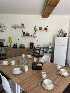 una mesa de madera con platos y tazas y una nevera. en Les Iris - Chambre Chêne, en Avanton