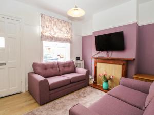 sala de estar con sofá y TV en Sole Bay Cottage en Lowestoft