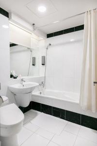 台北的住宿－多郎明哥商務旅館，白色的浴室设有卫生间、水槽和浴缸。