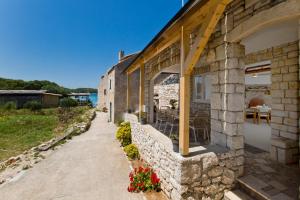 a stone building with a patio with flowers on it at Robinson house T'n'T in Hvar