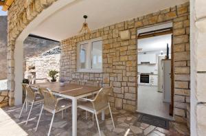 a stone walled kitchen and dining room with a table and chairs at Robinson house T'n'T in Hvar