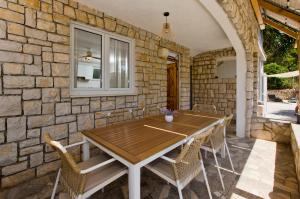 a stone walled patio with a wooden table and chairs at Robinson house T'n'T in Hvar