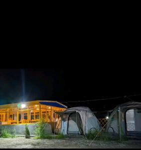 two tents in front of a building at night at Baseet Camping and Restaurant in Gulmit