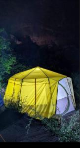 a yellow tent sitting on the ground at night at Baseet Camping and Restaurant in Gulmit