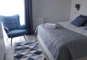 a bedroom with a bed and a blue chair at Apartamenty BEST HOME & SPA basen kryty in Ustronie Morskie +25 photos