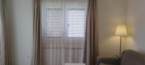 una ventana con cortinas blancas, una silla y una lámpara en Apartments Villa Elma, en Mošćenička Draga