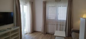 un soggiorno con TV e finestra di Apartments Villa Elma a Mošćenička Draga