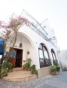 Kyrenia British Harbour Hotel في كيرينيا: مبنى أبيض أمامه نباتات خزف