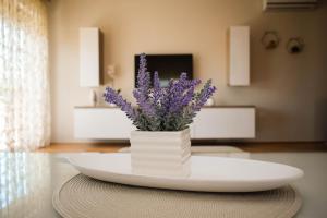um vaso branco com flores roxas sobre uma mesa em Apartman Villa Vita em Capljina