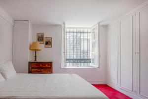 ein weißes Schlafzimmer mit einem Bett und einem Fenster in der Unterkunft Paris St Germain Charming in Paris