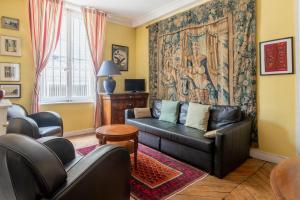 ein Wohnzimmer mit einem schwarzen Ledersofa und einem Teppich in der Unterkunft Paris St Germain Charming in Paris