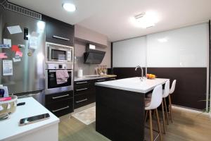 a kitchen with black cabinets and a kitchen island with a sink at Chalet junto a la Ciudadela de Jaca in Jaca