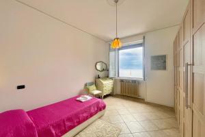 um quarto com uma cama rosa e uma janela em Casa Valentina em Menaggio