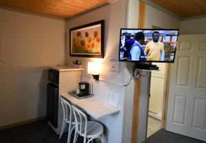 a room with a tv on a wall with a table at Motel Riviere Trois Pistoles in Trois-Pistoles