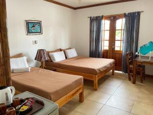 a hotel room with two beds and a desk at Tipolo Beach Resort in Moalboal