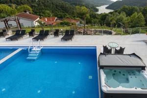 a large blue swimming pool with a view of a river at Quinta Flor de Lis, Gerês in Vieira do Minho