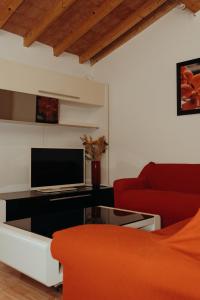 a living room with a red couch and a television at La Dolce Vita Cittadella in Pitigliano