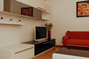 a living room with a red couch and a television at La Dolce Vita Cittadella in Pitigliano