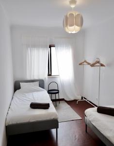 a bedroom with two beds and a lamp and a window at Caparica Coast Townhouse Apartments in Charneca