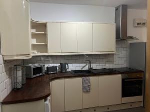 a kitchen with white cabinets and a sink and a microwave at Ground Floor Two Bed Cairo Street in Warrington