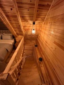 Zambula bungalov في طرابزون: غرفة خشبية فيها سرير ودرج