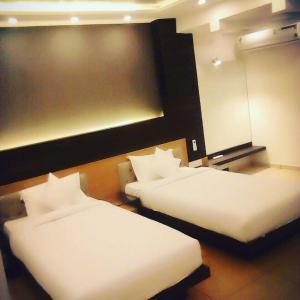 2 camas en una habitación de hotel con sábanas blancas en HOTEL AL AMANA TOWER en Kondotti