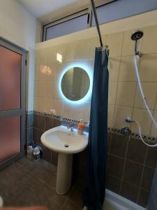 uma casa de banho com um lavatório, um espelho e um chuveiro em ADRIATIC Seaview Apartments em Durrës