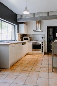 a kitchen with white cabinets and a tile floor at Maison Madeleine in La Flèche