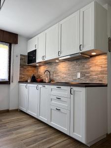 a kitchen with white cabinets and a brick wall at Monolocale in centro a Campiglio, ad 80mt dagli impianti in Madonna di Campiglio