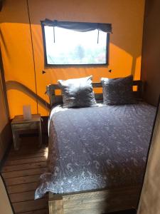 een bed in een kamer met een raam bij Camping Le Mondou in Saint-Julien-de-Lampon