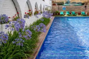 Una piscina con flores moradas y sillas azules. en Apartaments Atzavara, en Calella