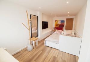 a white bedroom with a bed and a mirror at The Beach Box By Air Premier in Seaford