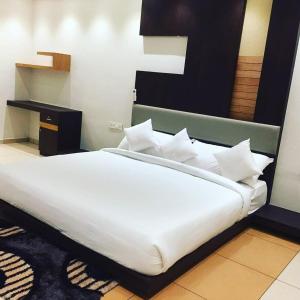 uma cama grande com lençóis brancos e almofadas num quarto em HOTEL AL AMANA TOWER em Kondotti