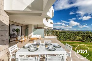 ミハス・コスタにあるViVi Homes - Blue View Pool, Sauna, Gym & Sea Viewの家のパティオ(白いダイニングテーブル、椅子付)
