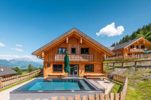 a log house with a swimming pool in front of it at Poolchalet Dachsteinblick in Pruggern