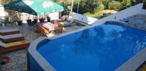 una gran piscina azul con una sombrilla verde en Apartment Bradex Dreams, en Bečići