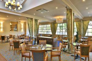 a restaurant with tables and chairs and windows at Reigate Manor Hotel in Reigate