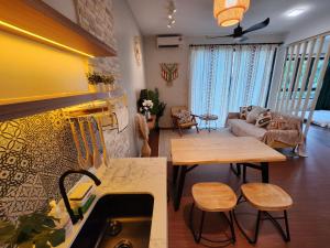 a kitchen with a table and a living room at Unique Boho Style Condo with NETFLIX for up to 5PAX - Enjoy Mountain View while swimming at the Infinity Pool & Natural Hotspring Pool, 2mins walk to the Lost World of Tambun, Water Themepark at IPOH in Ipoh