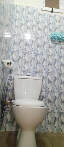 a white toilet in a bathroom with a tiled wall at RÈSIDENCE NGUARY in Dakar