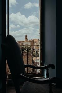 einen Stuhl auf einem Balkon mit Blick auf ein Fenster in der Unterkunft Casa Caracciolo in Pitigliano