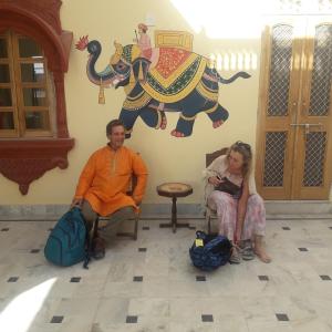 a man and a woman sitting in front of a wall with an elephant at Desert Sun Homestay in Bikaner