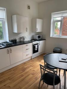 a kitchen with white cabinets and a table and a dining room at 2 bed apartment complete with bedding and towels in Wellington
